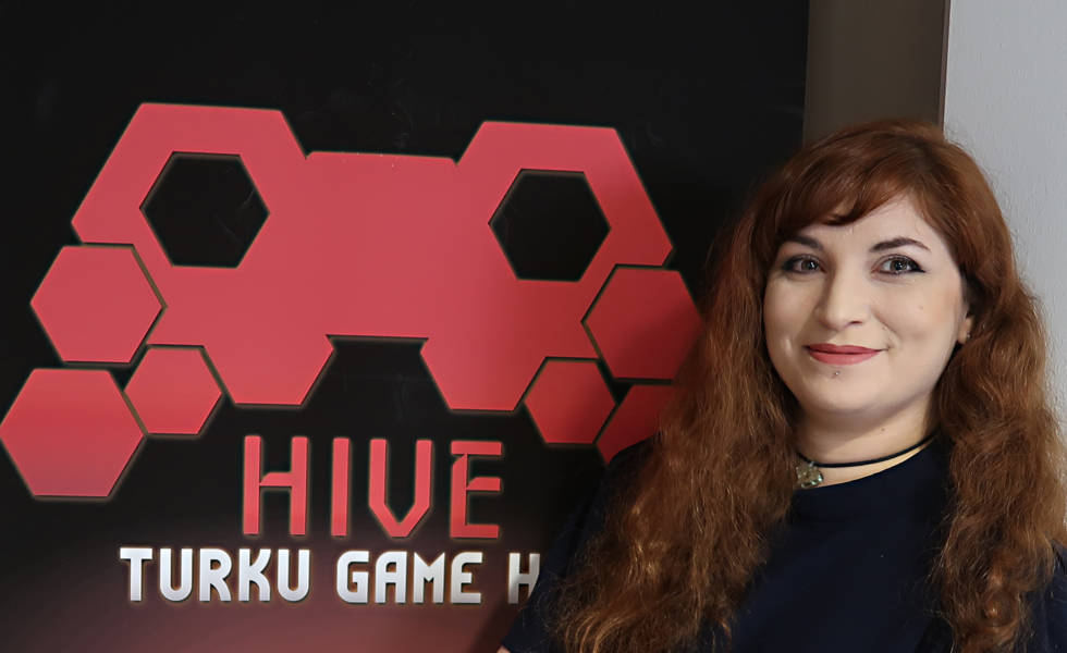 Ruskeatukkainen nainen Hive Turku Game Labin logon vieressä.