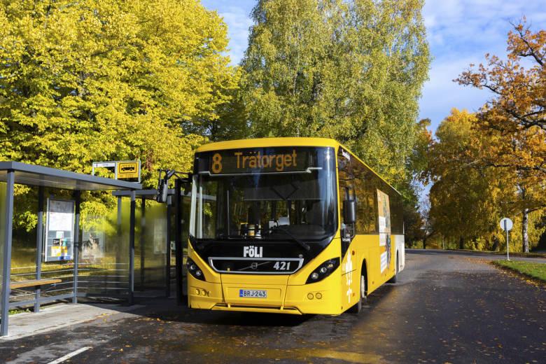 Keltainen kaupunkiliikenteen bussi seisoo pysäkillä syysauringossa.