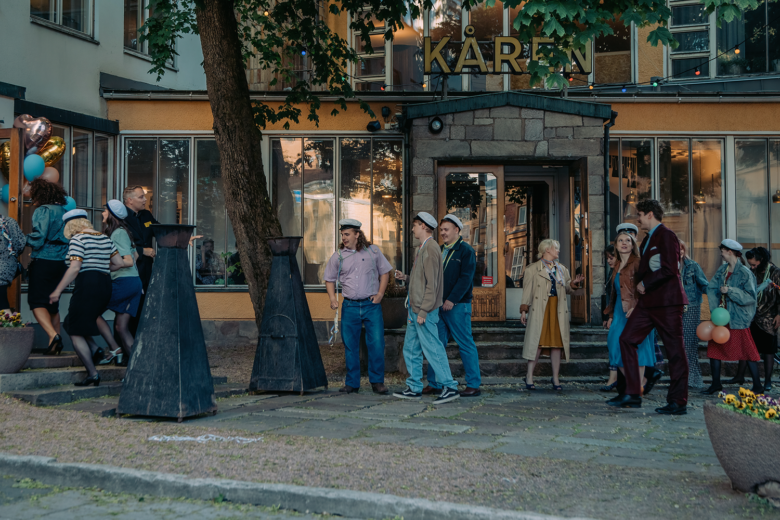 Nuoret ylioppilaat juhlivat ylioppilaslakit päässään oranssin Kåren-ravintolan edessä. 